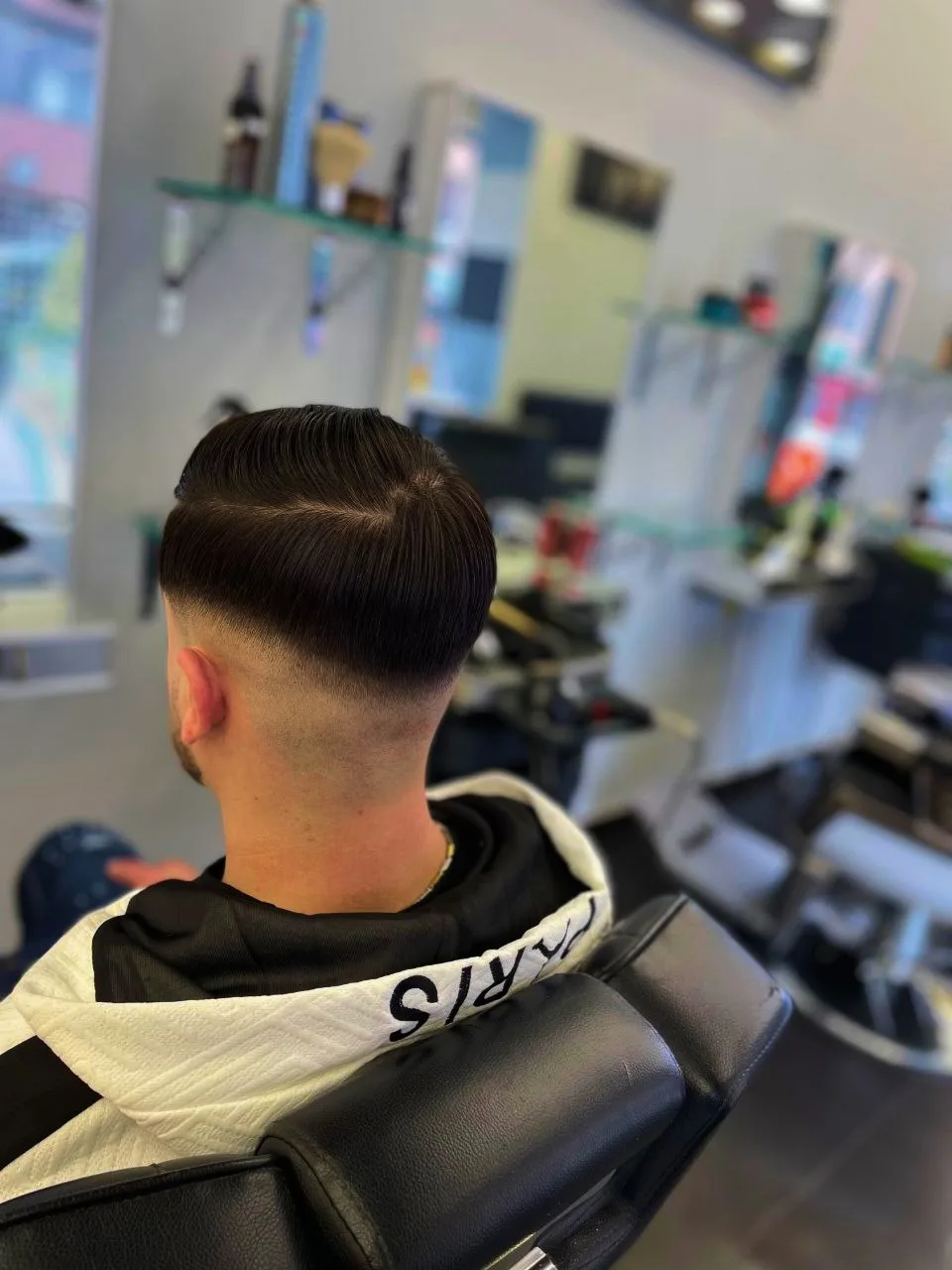 Tunsoare pentru bărbați cu fade jos și păr negru lung pe creștet, realizată în salonul Magic