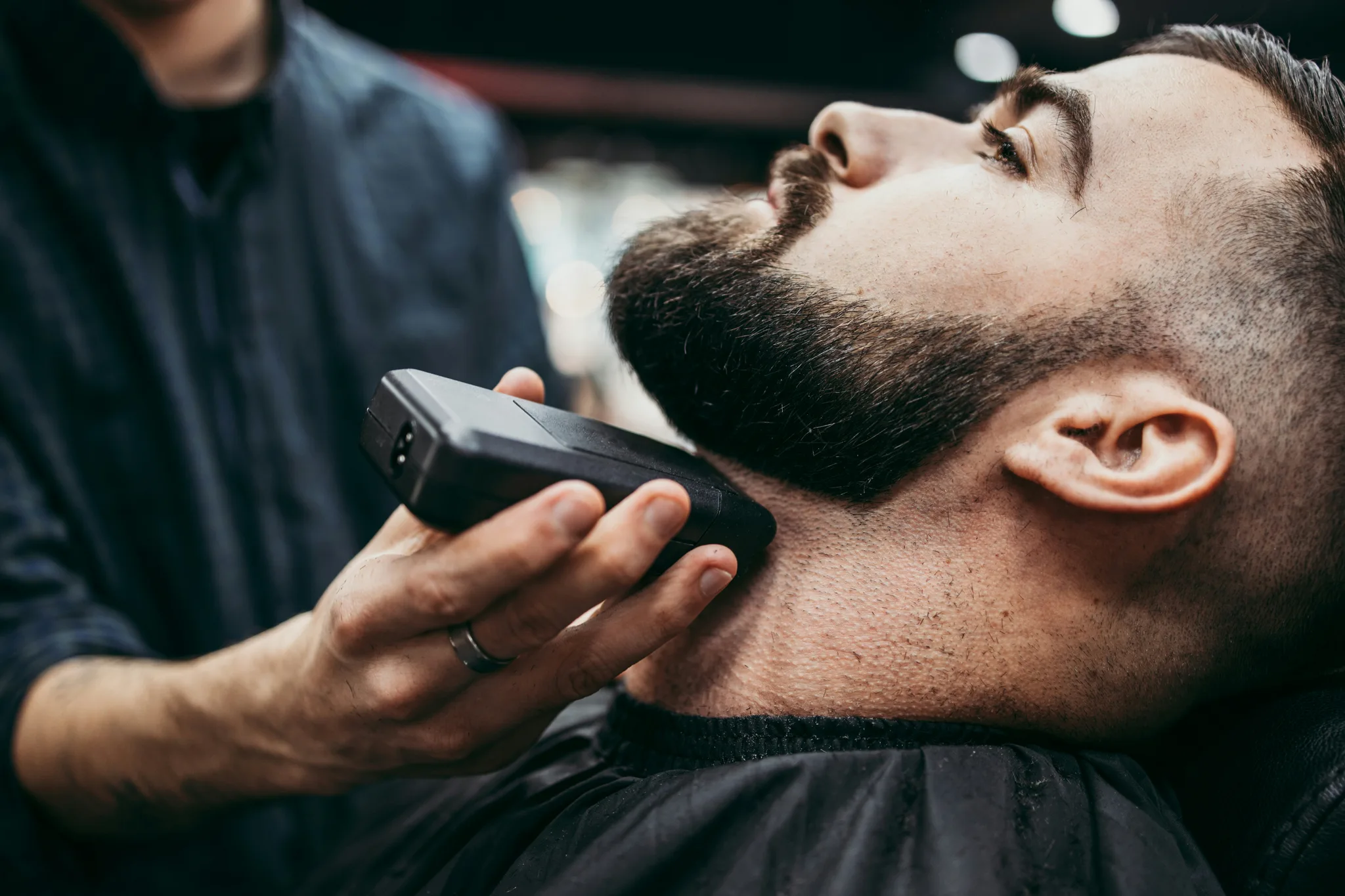 Tuns și conturat barbă cu trimmerul într-un salon de frizerie pentru bărbați