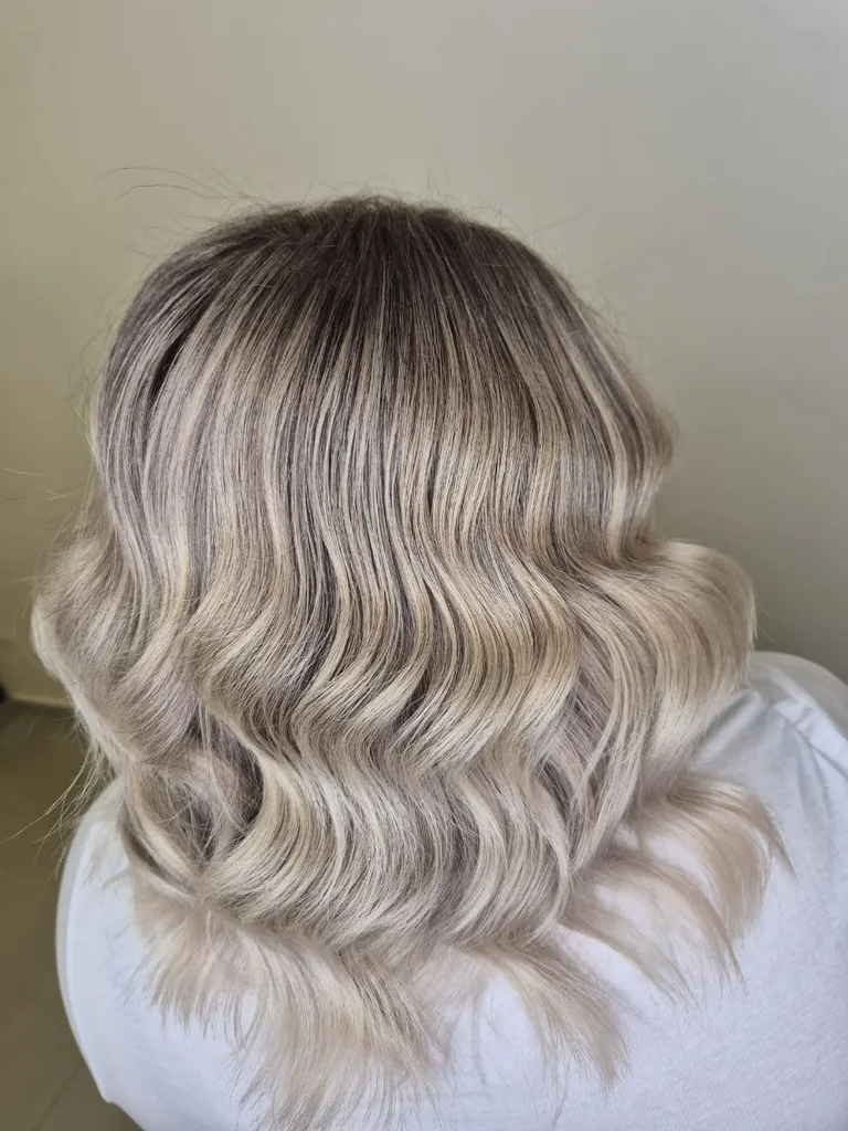 Păr cu rădăcină închisă și lungimi blond cenușiu, bucle largi, lungime medie