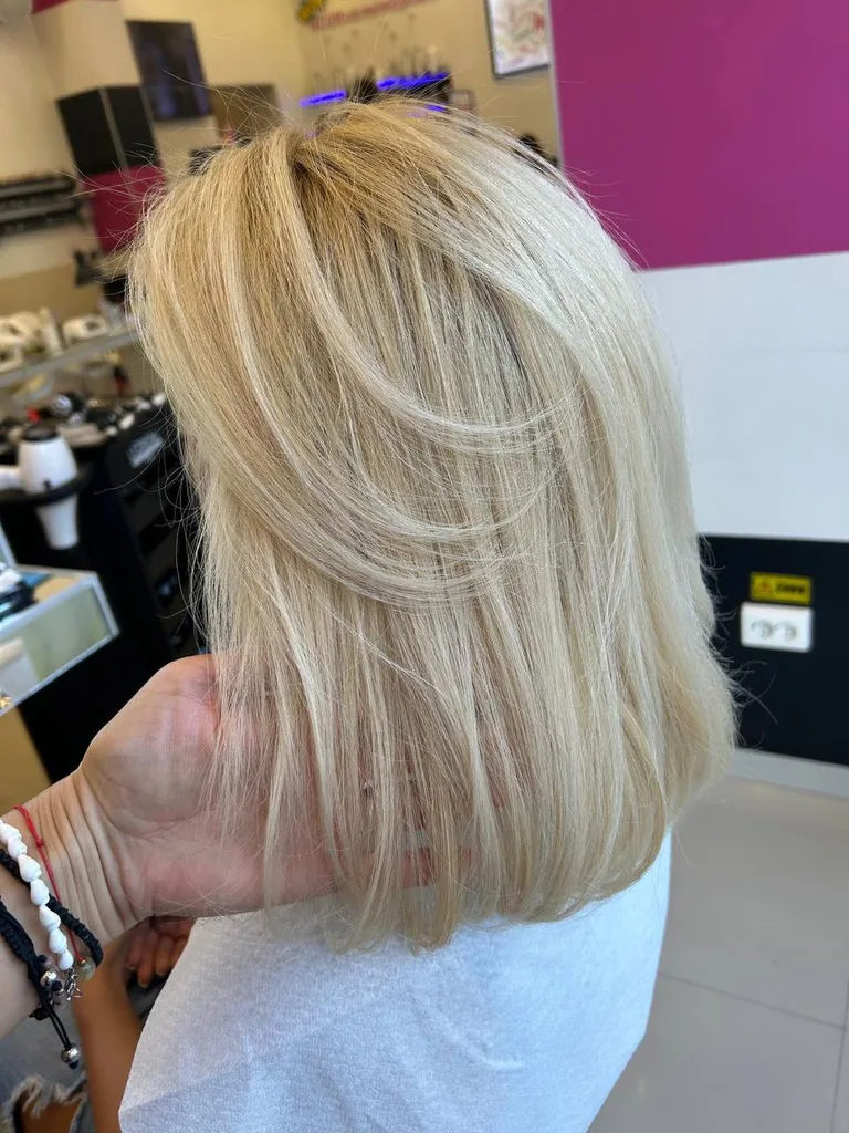 Păr blond auriu în straturi, lungime medie, coafat cu volum