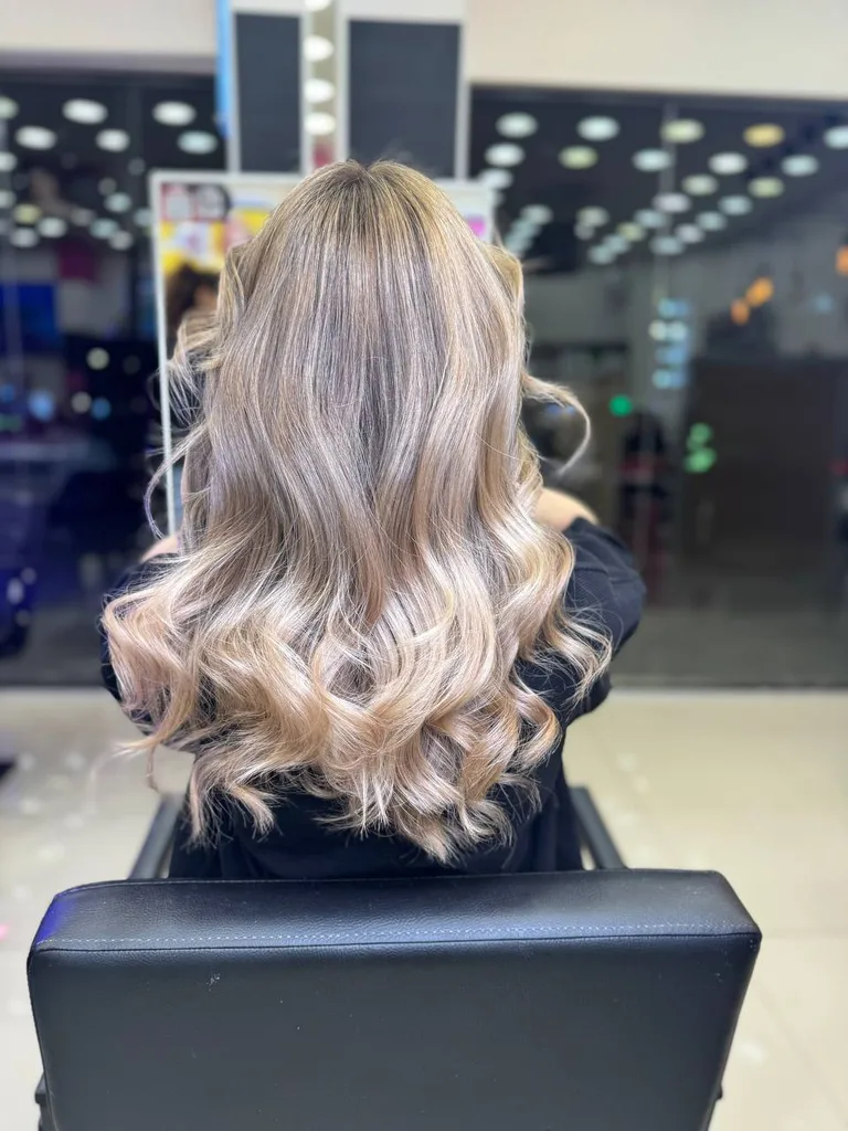 Balayage blond pe păr lung cu bucle, văzut din spate