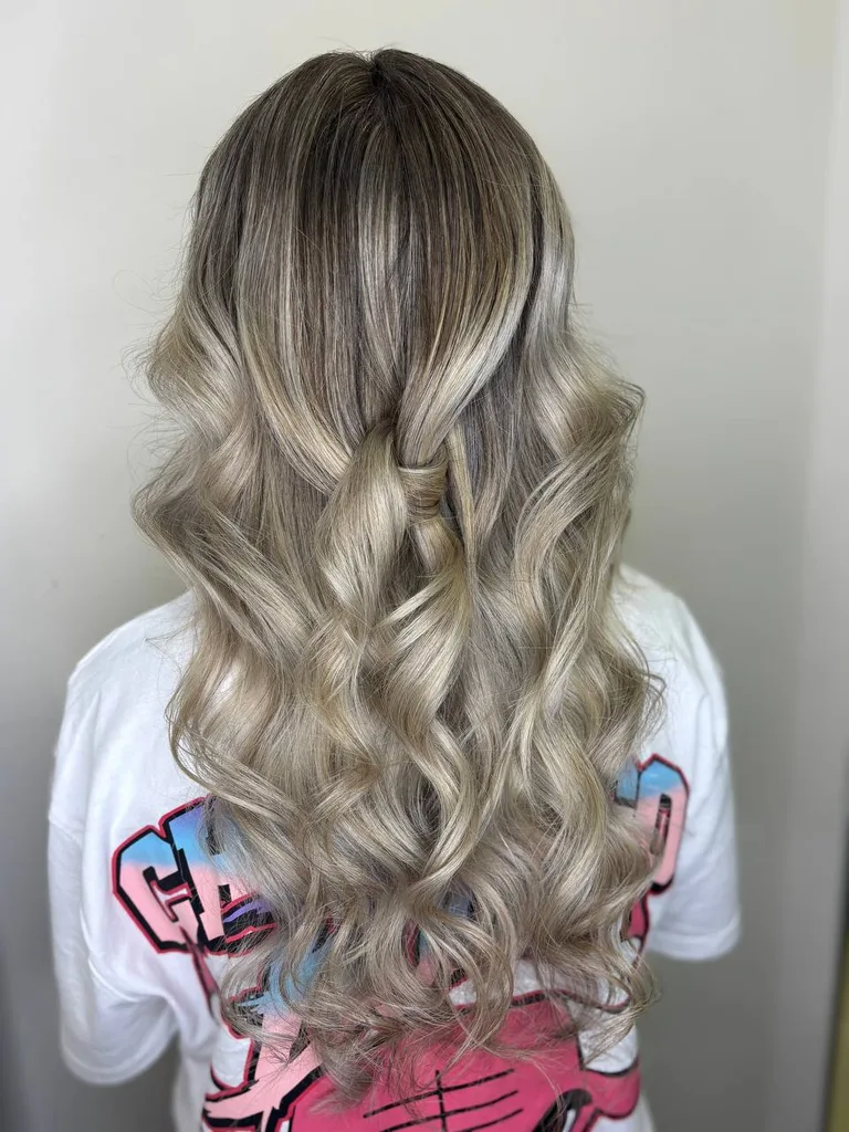 Balayage blond cenușiu pe păr lung cu rădăcină închisă și bucle bogate