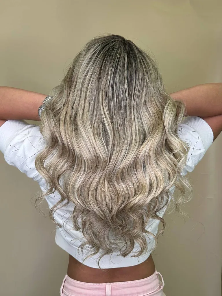 Balayage blond cenușiu pe păr lung cu bucle