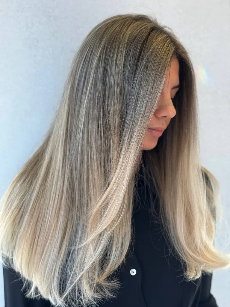 Balayage blond pe păr lung și drept, cu rădăcină închisă, din profil